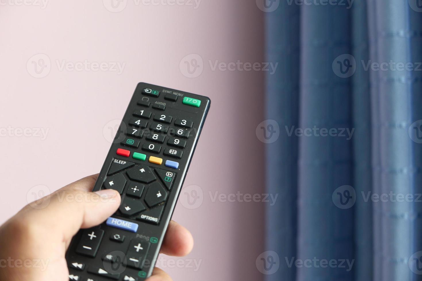 Cerca de la mano del hombre sujetando el control remoto del televisor foto