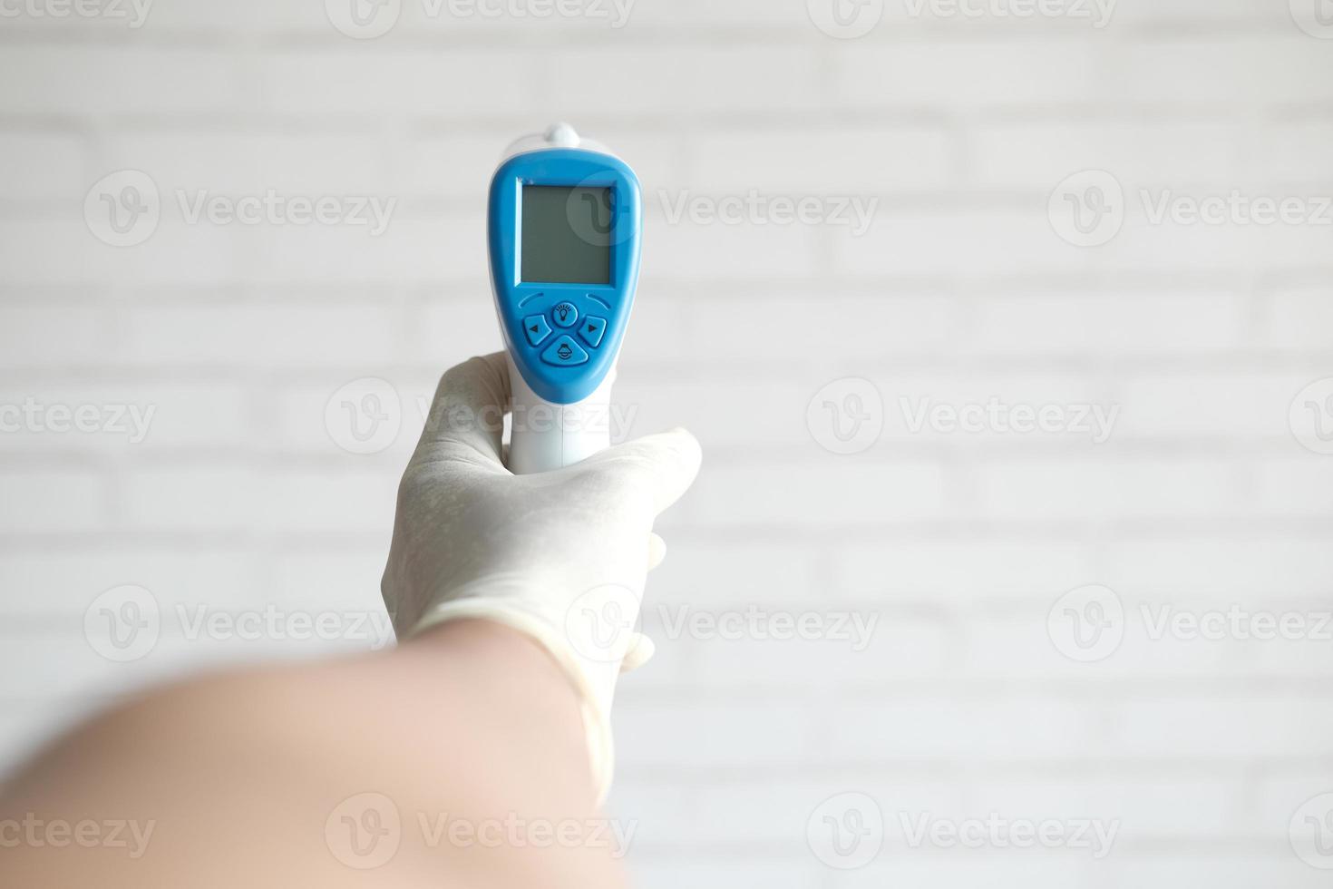 Hand holding infrared thermometer to measuring temperature. photo