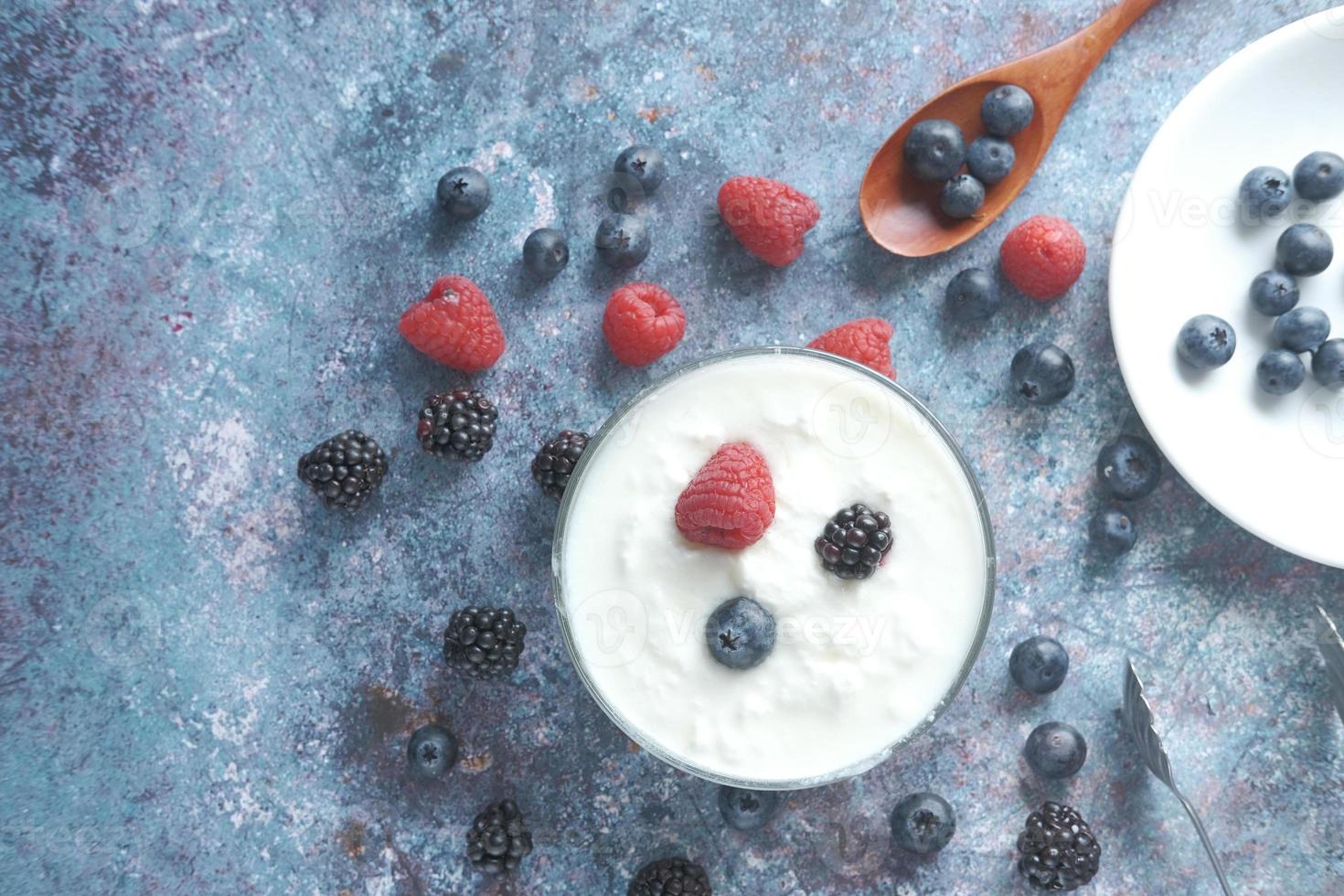 Cerca de yogur fresco con bayas azules en un recipiente foto