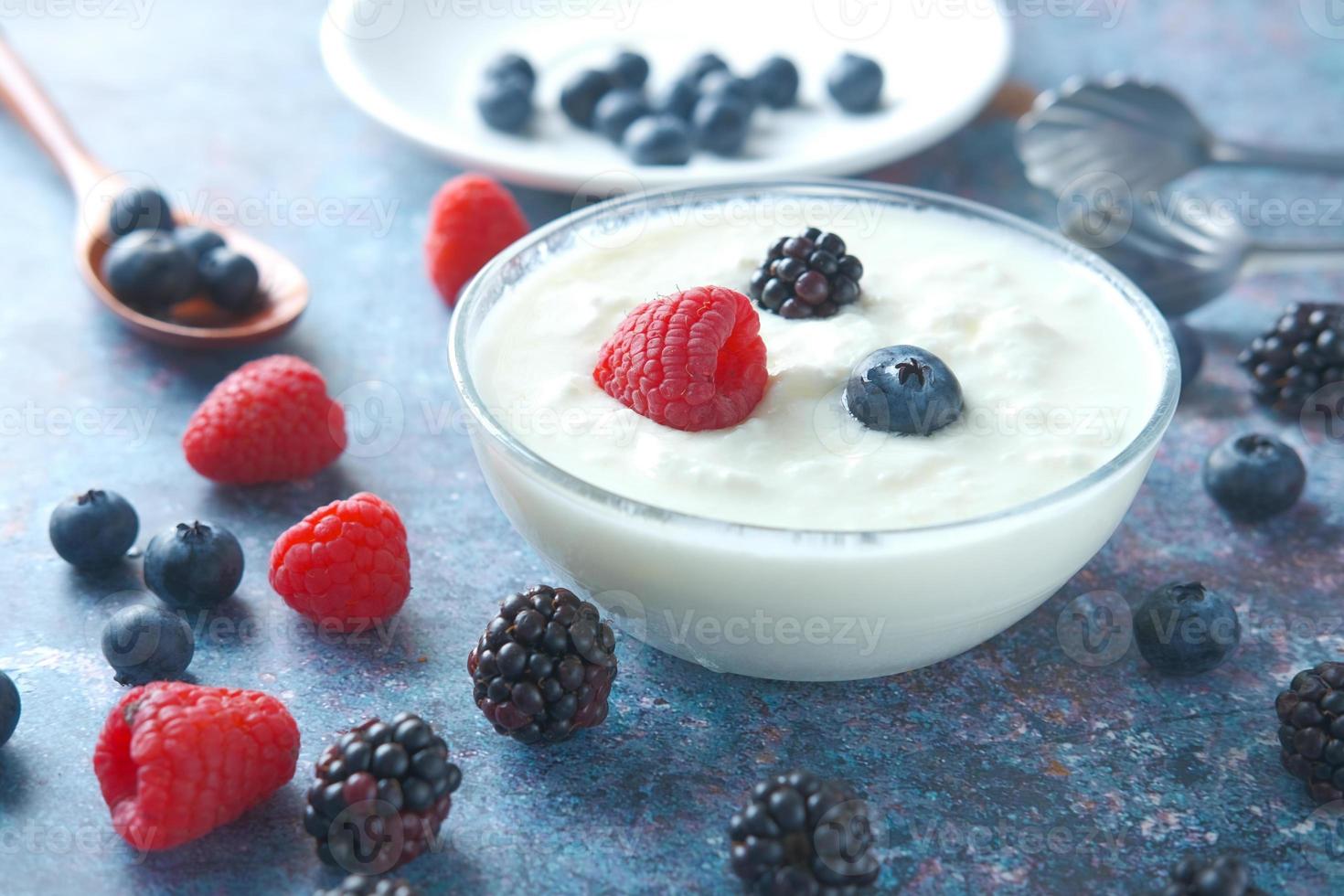 Cerca de yogur fresco con bayas azules en un recipiente foto