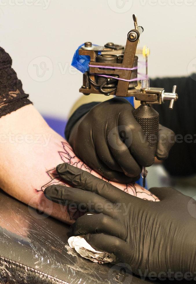 Tattoo artist draws a flower on a person's arm photo