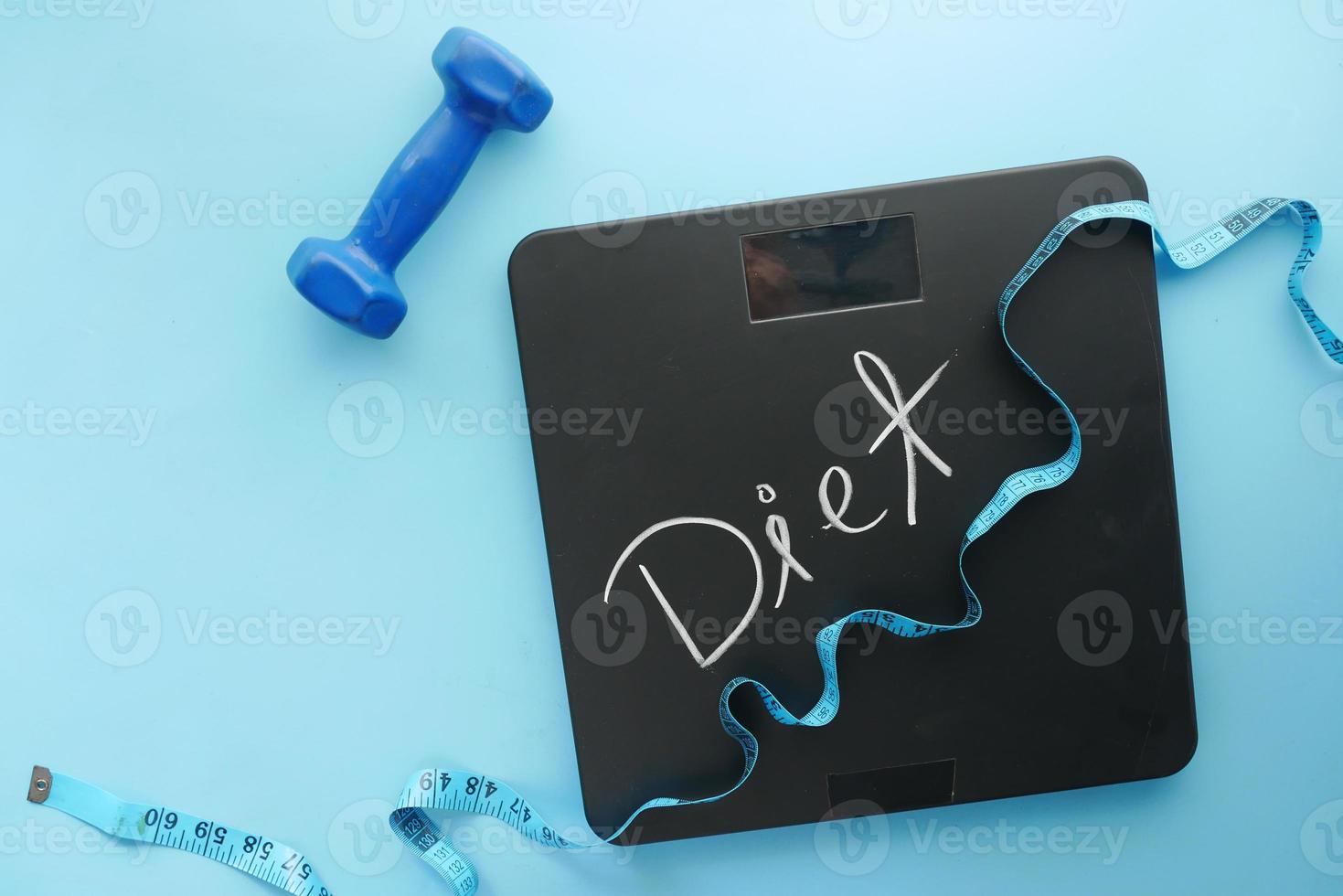 Diet text on weight scale with dumbbell and measurement tape on blue photo