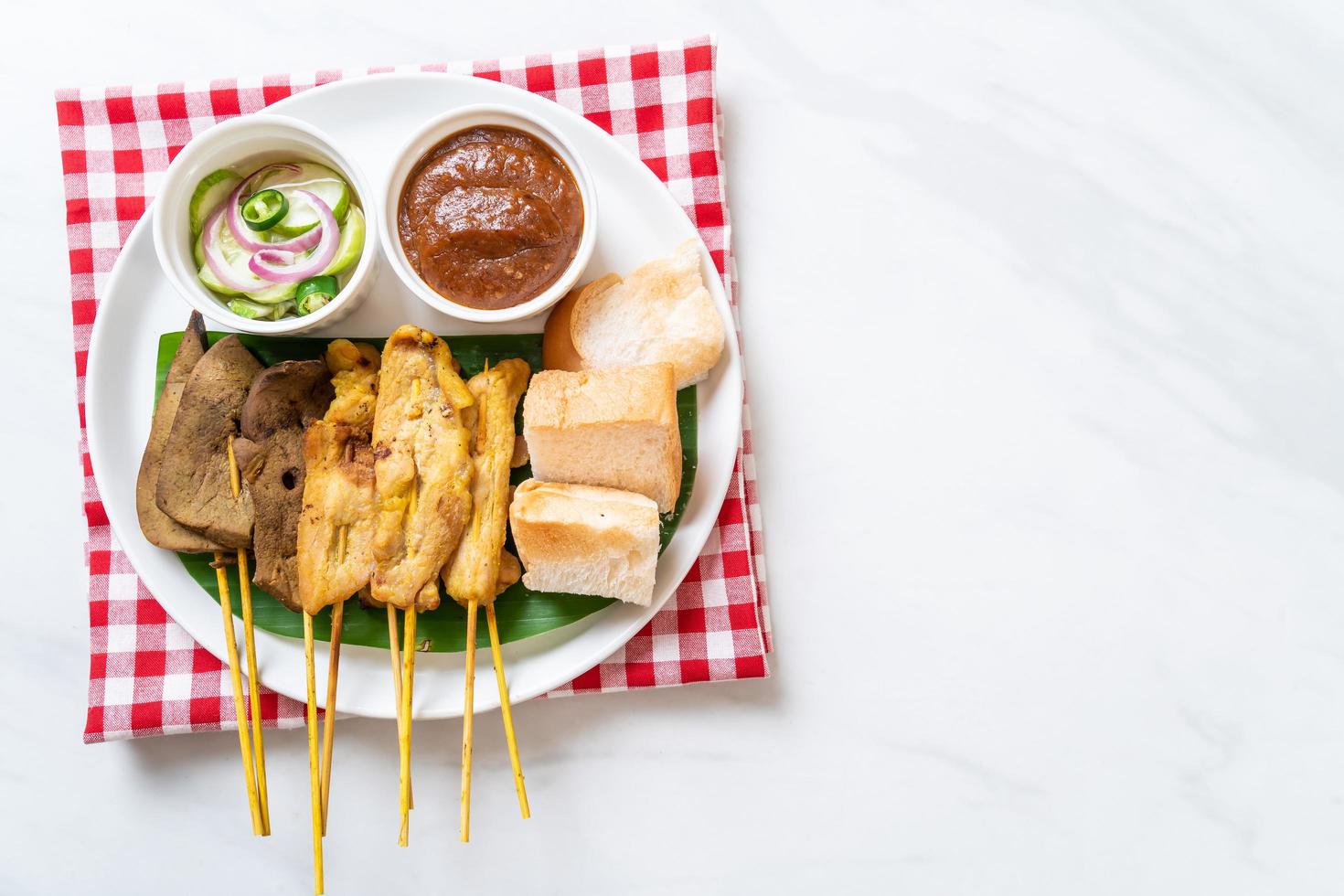 Pork Satay with your Peanut Sauce  and pickles which are cucumber slices and onions in vinegar photo