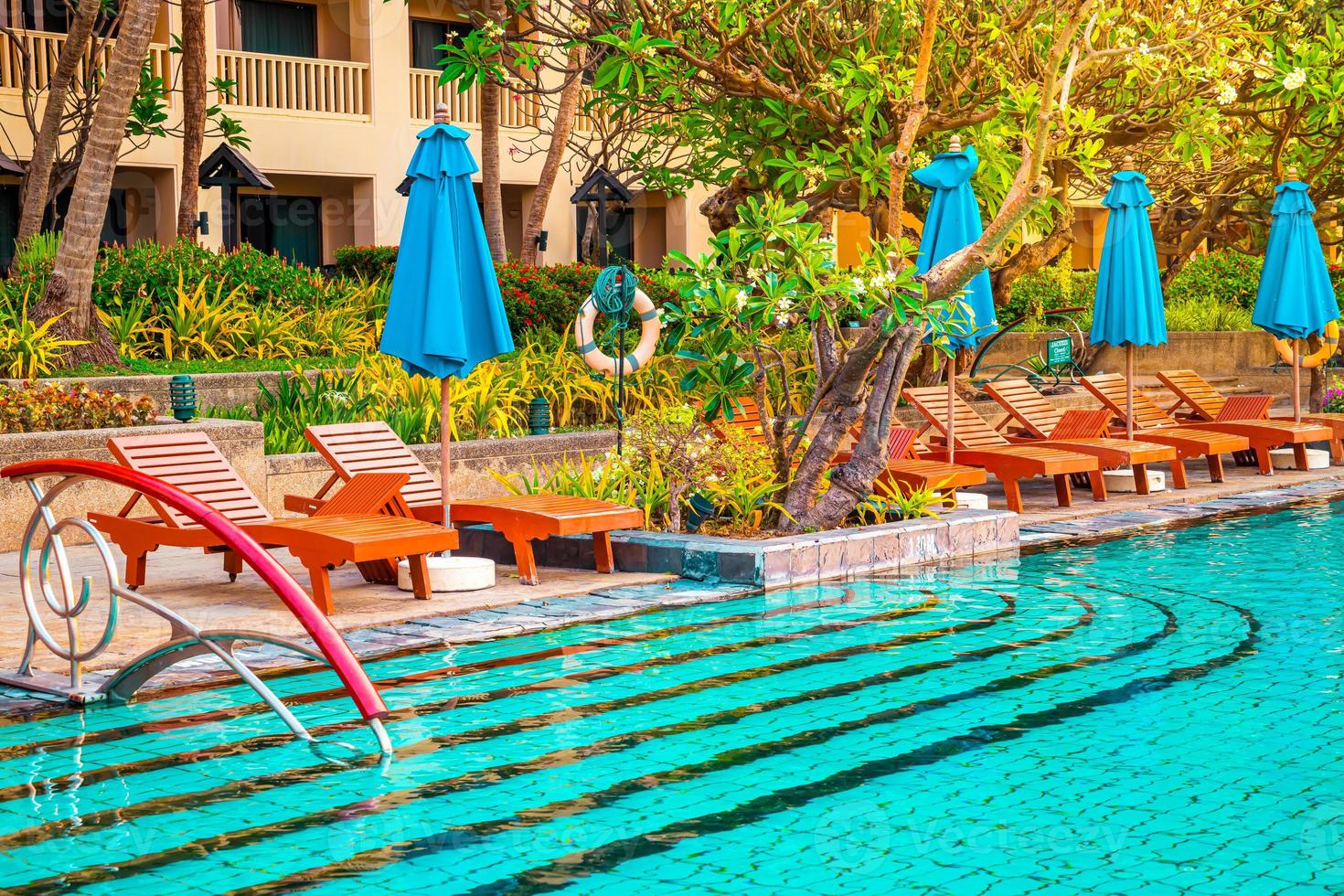 Beautiful umbrella and chair around swimming pool in hotel and resort photo