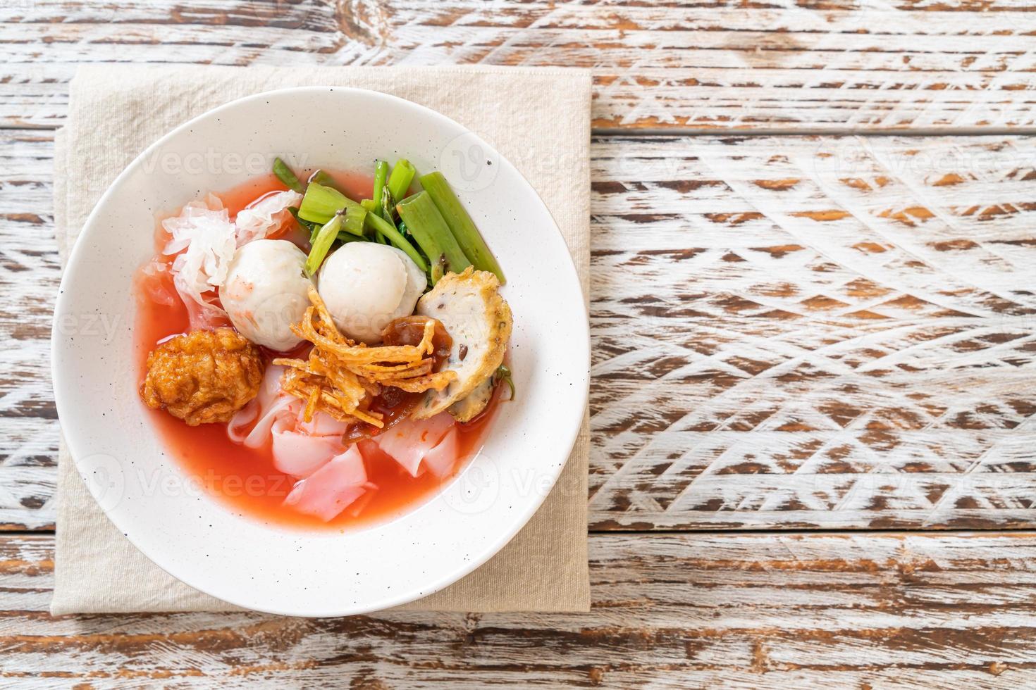 Fideos estilo tailandés con tofu surtido y bola de pescado en sopa roja foto