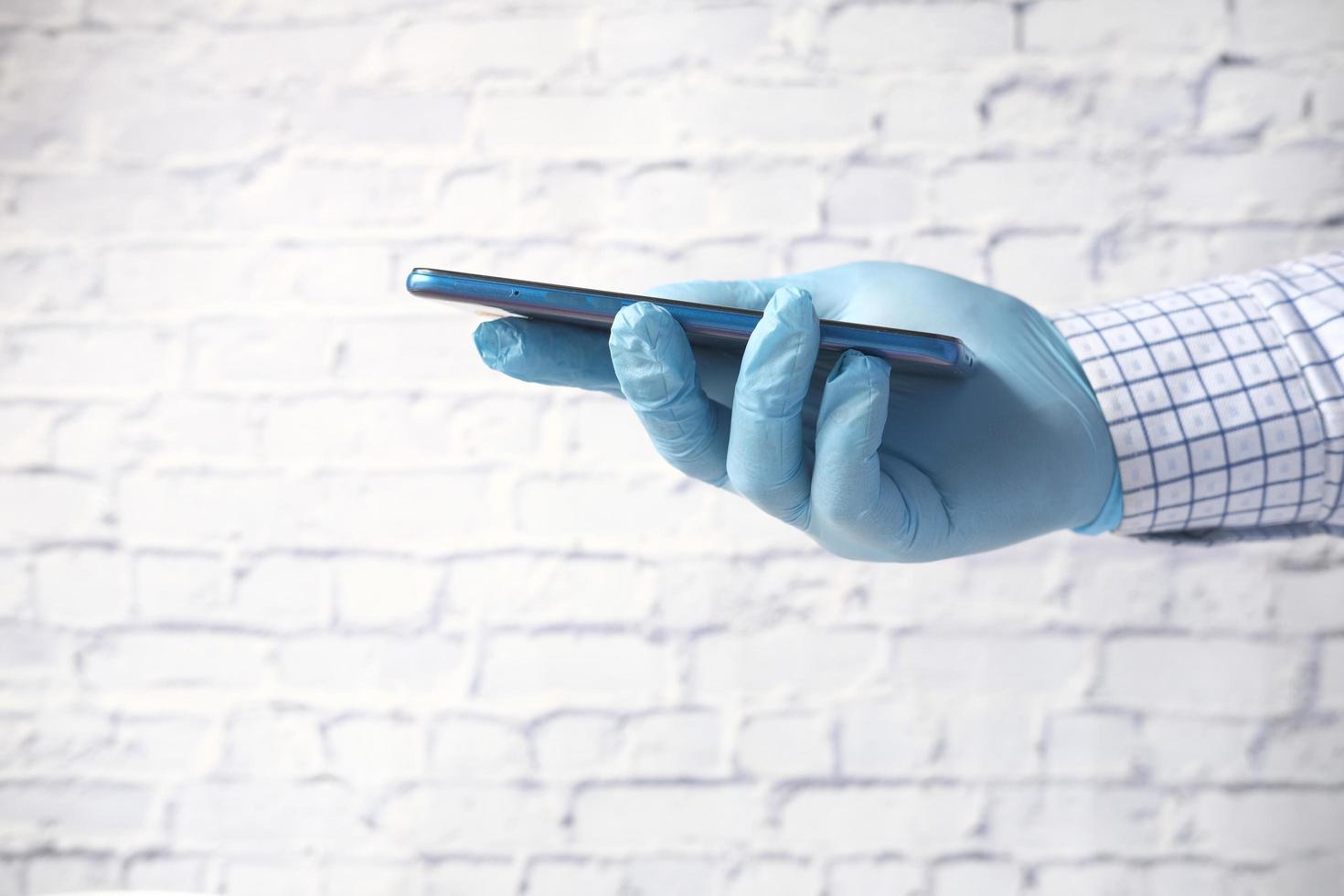 Hand in latex gloves holding smart phone with green screen photo