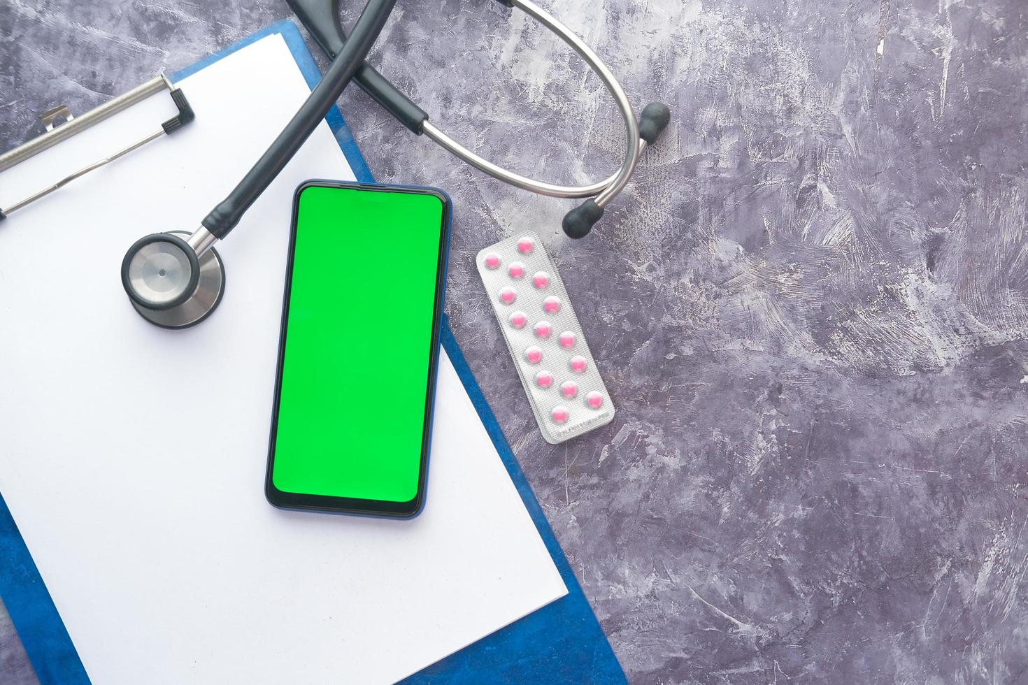 Top view of smart phone and stethoscope on clinic table photo