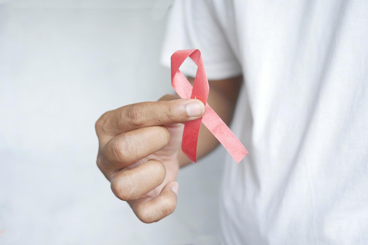 Hand holding red HIV ribbon with copy space photo