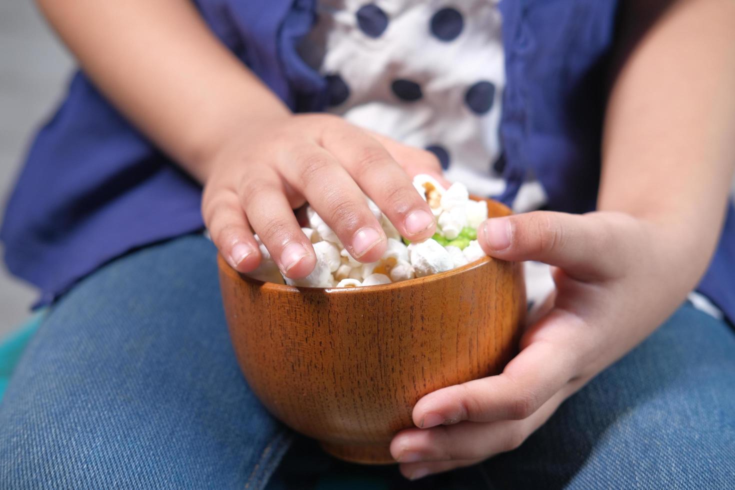 Child girl hand holding a bowl of colorful popcorn photo