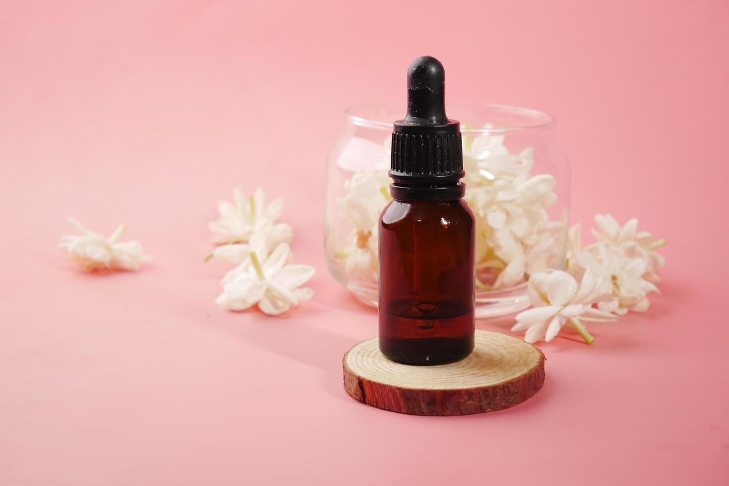 Eucalyptus essential oils in a glass bottle and flower on pink background photo