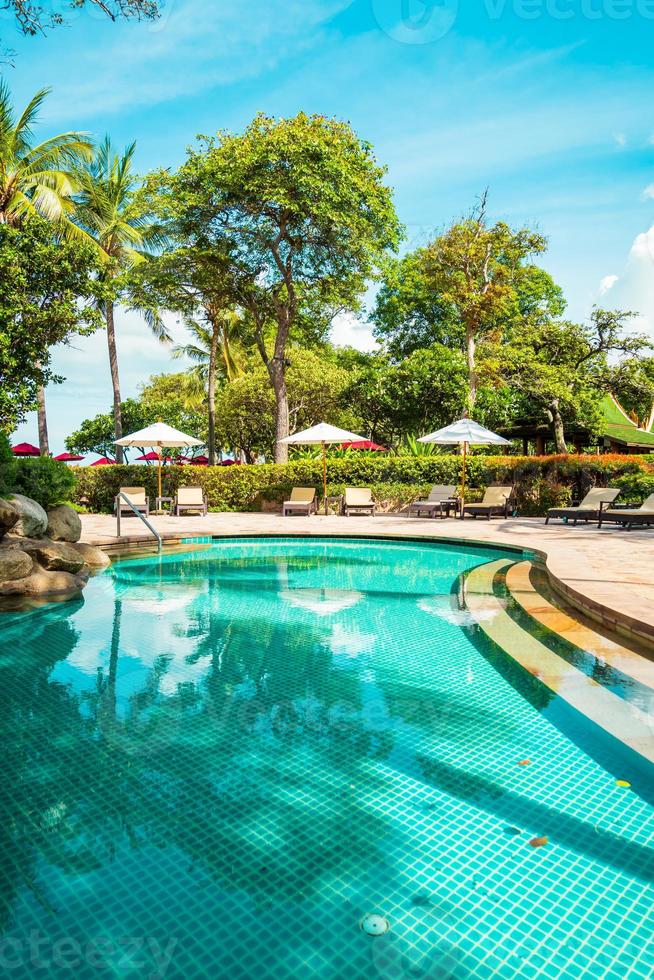 Beautiful tropical beach and sea with umbrella and chair around swimming pool in hotel resort photo