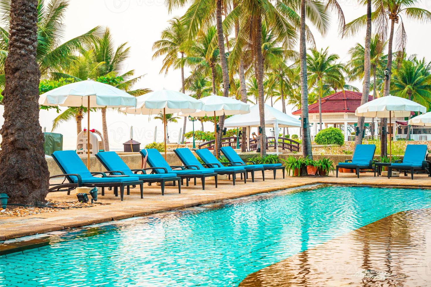 Hermosa sombrilla y silla alrededor de la piscina en el hotel y resort foto