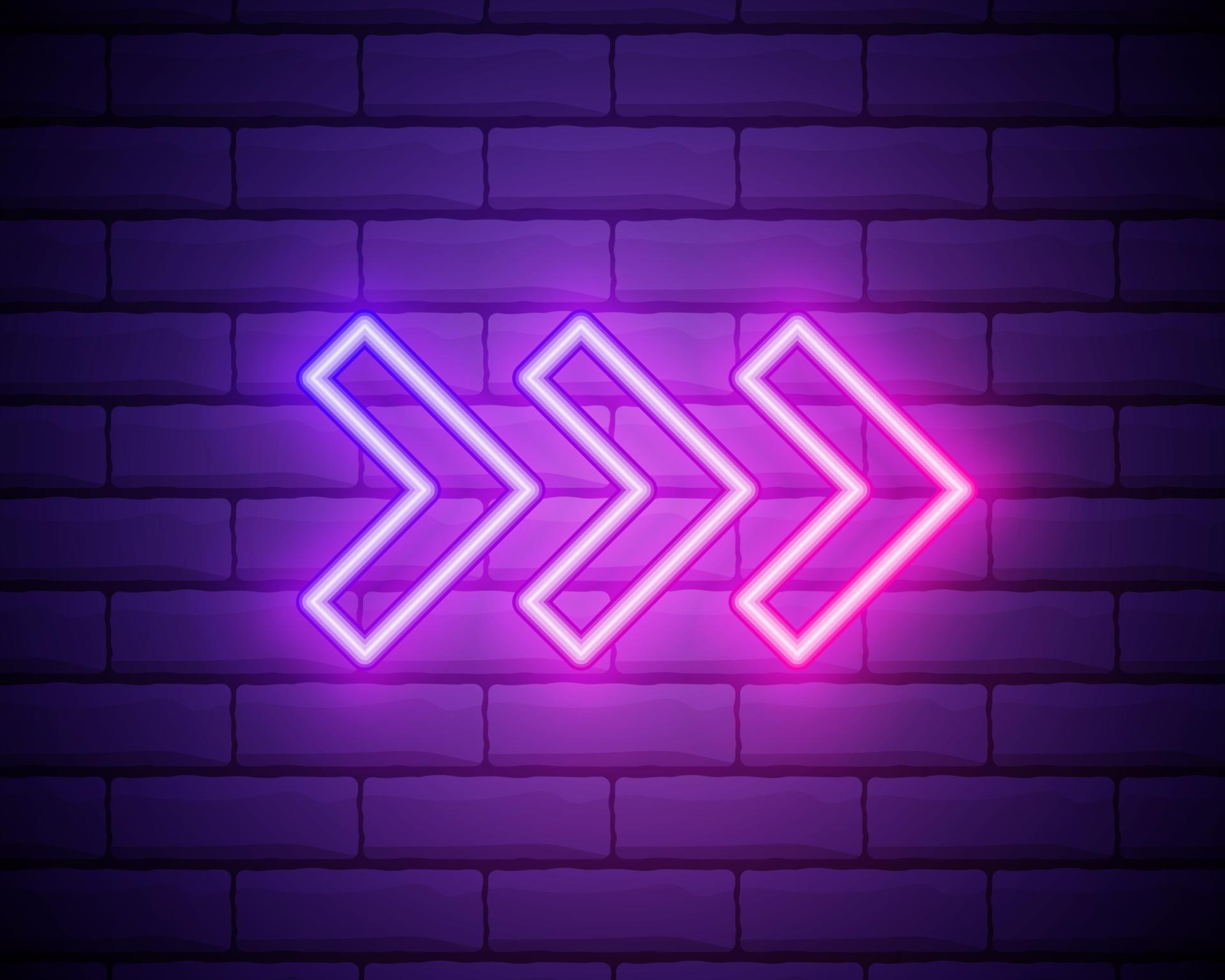 Neon arrow sign. Glowing neon arrow pointer on brick wall background
