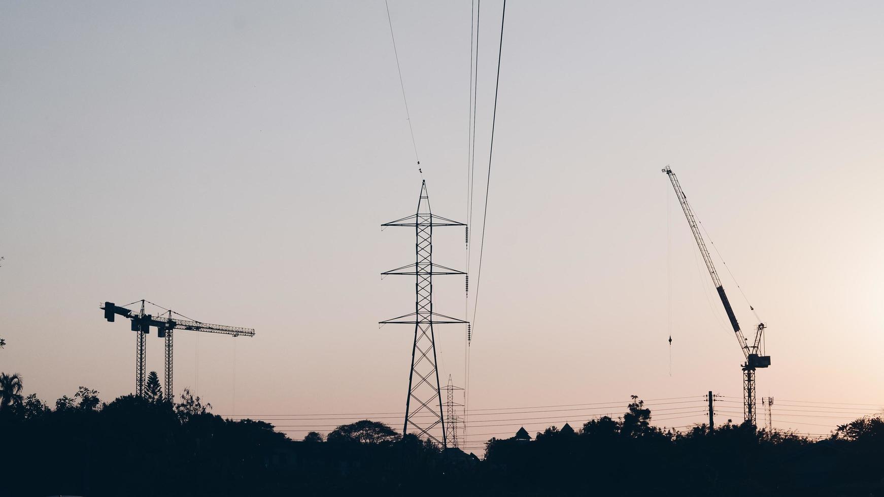 Fondo industrial abstracto con siluetas de grúas de construcción sobre el increíble cielo del atardecer foto