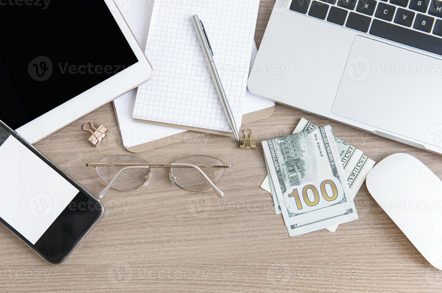 Laptop with office supplies and money on the table. photo