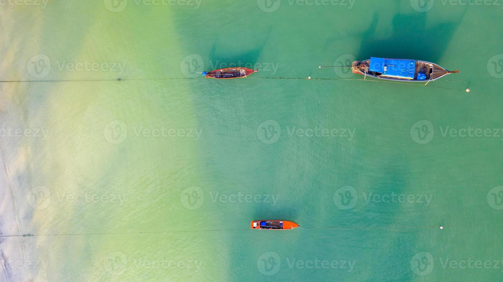 Vista aérea superior, barco de pesca, barco turístico flotando en un mar claro y poco profundo, hermosa agua azul brillante en el océano foto