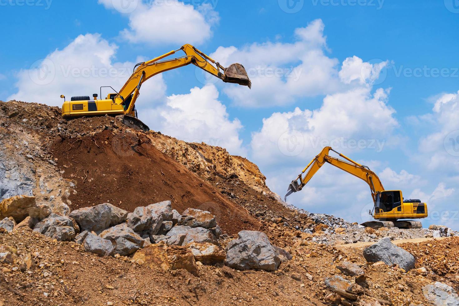 Excavators and stone crushing machine of mining under a blue sky with clouds photo