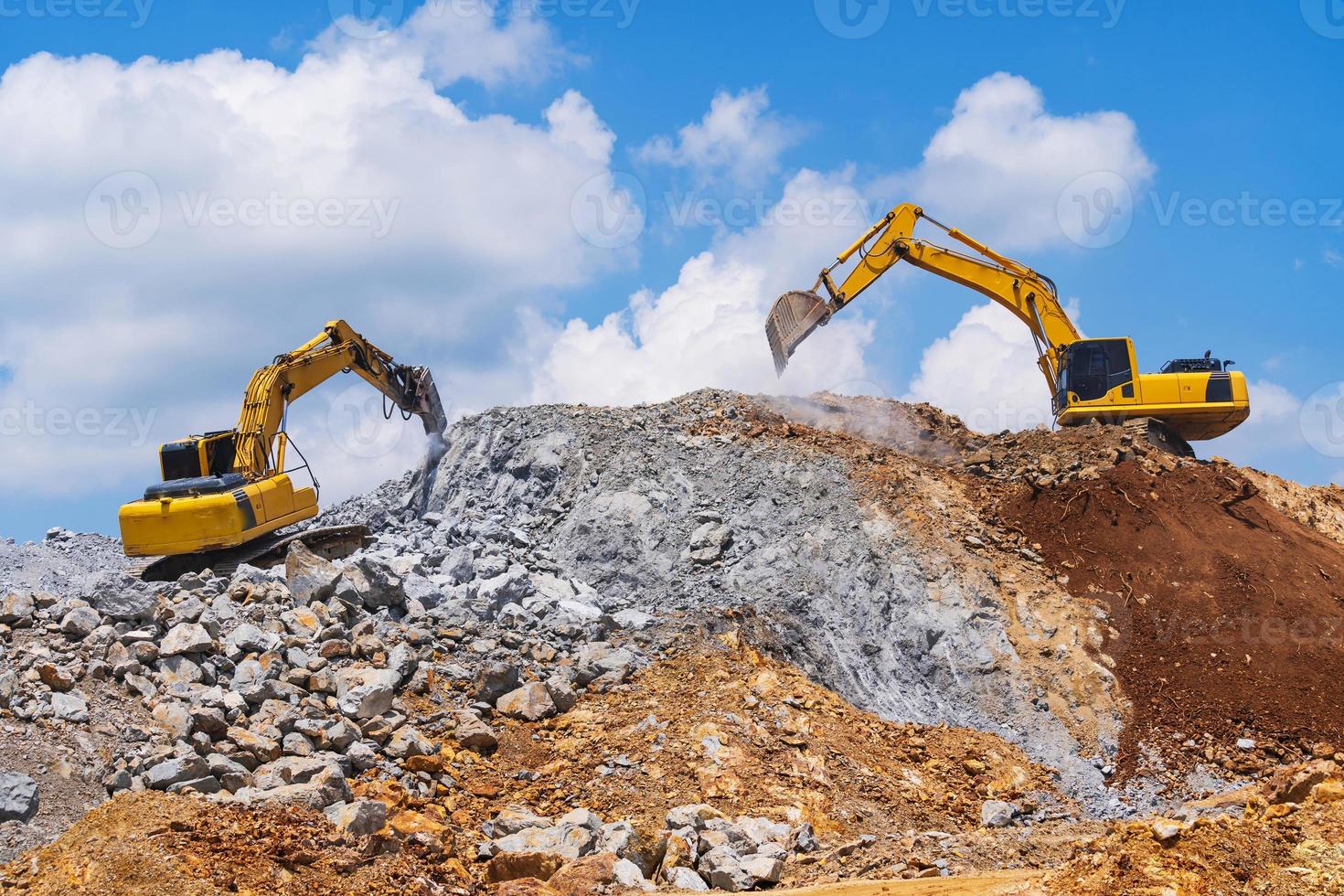 Excavators and stone crushing machine of mining under a blue sky with clouds photo