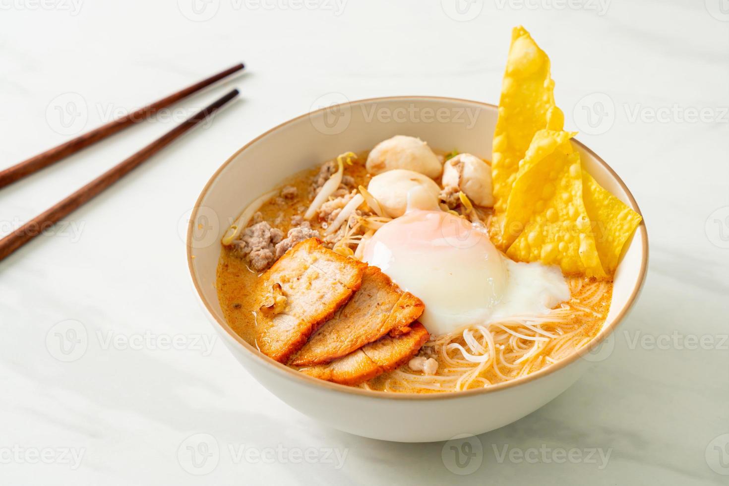 Rice vermicelli noodles with meatball, roasted pork and egg in spicy soup photo