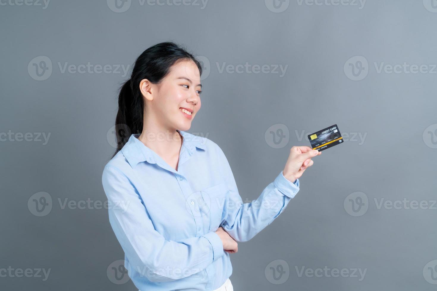 Portrait of a lovely young Asian woman showing credit card photo