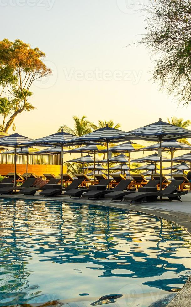 Sombrilla y cama de piscina alrededor de la piscina al aire libre en el hotel resort para viajes vacaciones vacaciones foto