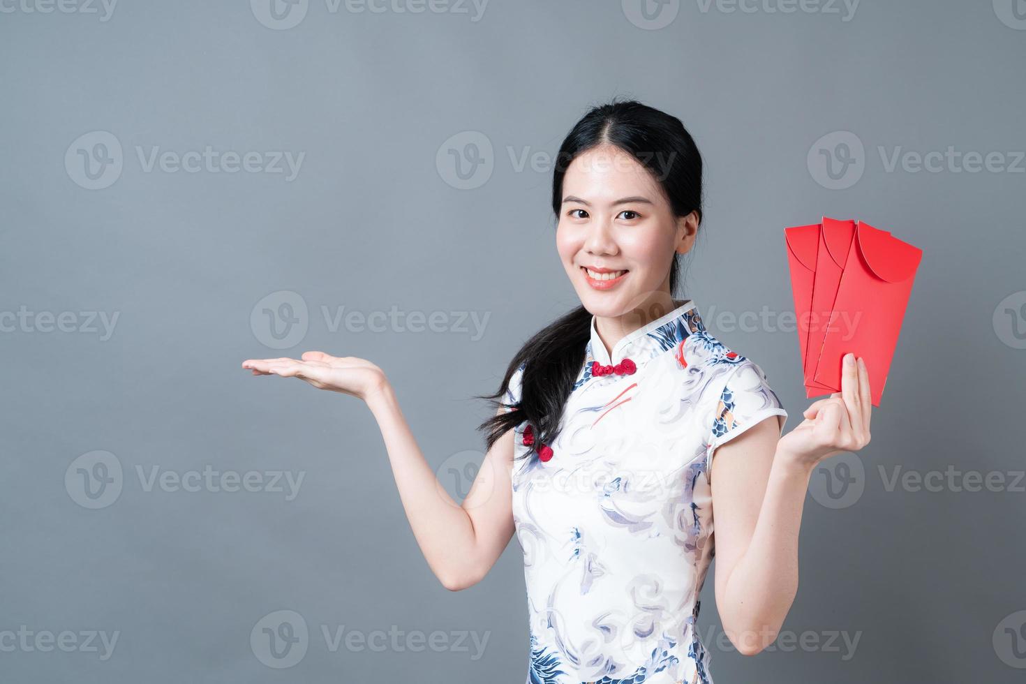 Mujer asiática vistiendo traje tradicional chino con sobre rojo o paquete rojo foto