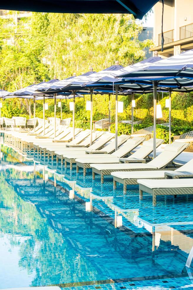 Umbrella and pool bed around outdoor swimming pool in hotel resort for travel holiday vacation photo