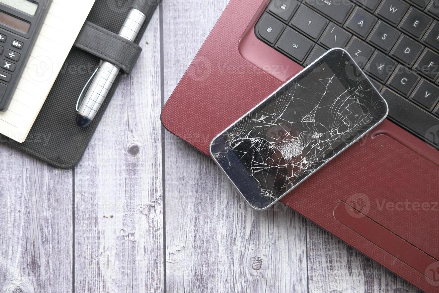 Top view of broken smart phone on laptop on table photo
