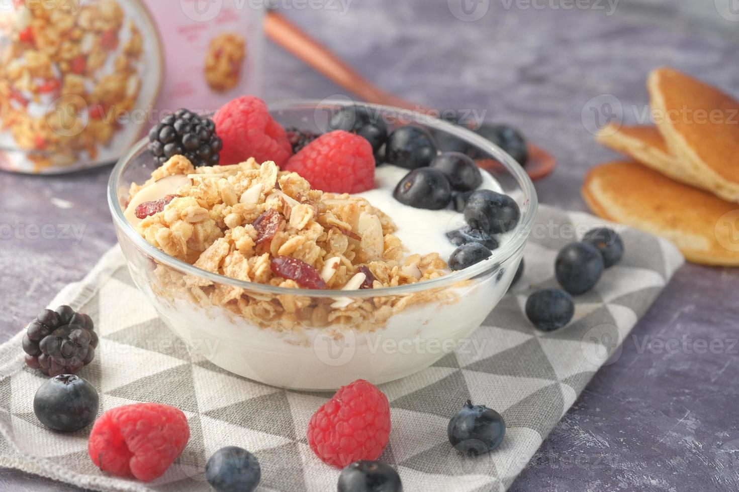 Granola and berries in bowl on pink background photo