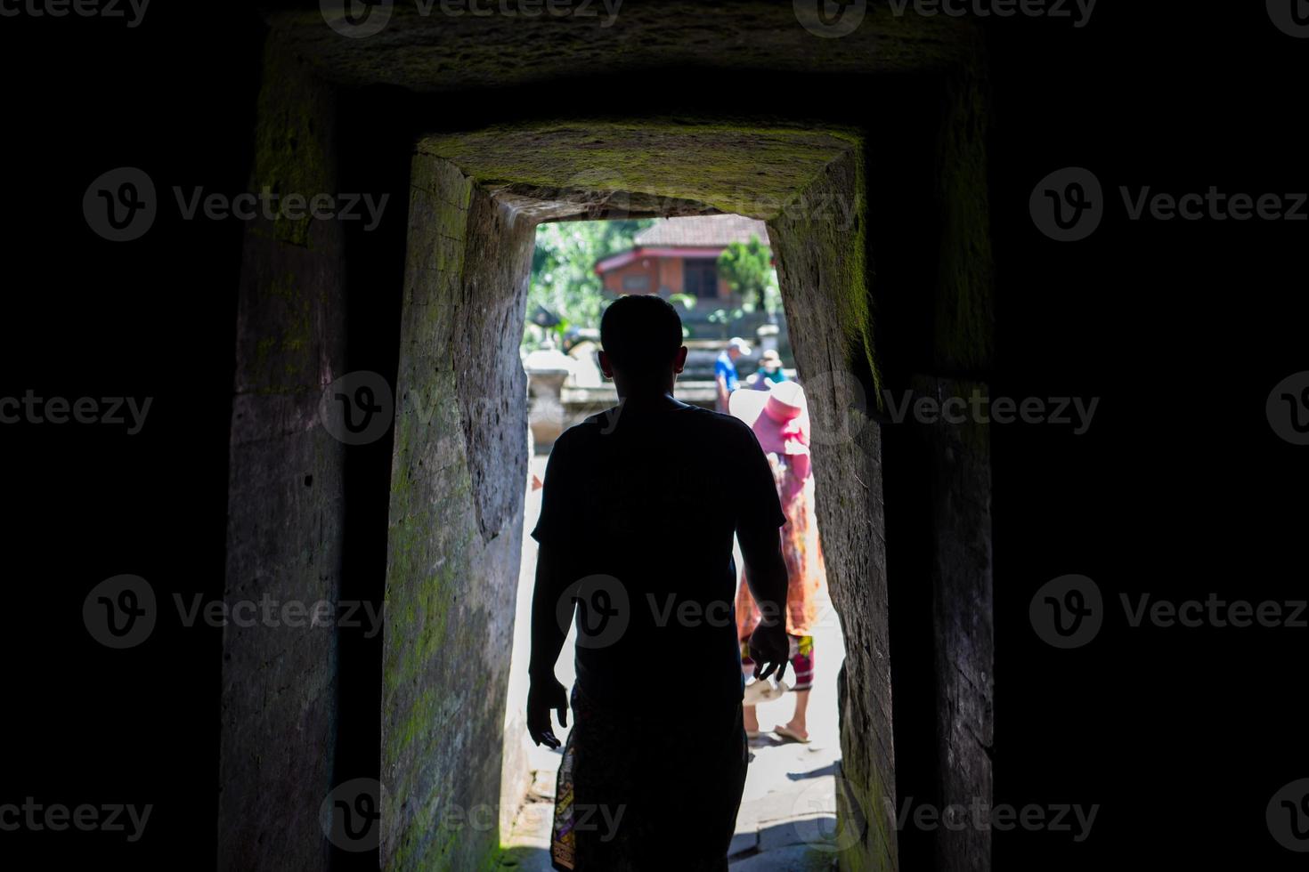 Silhouette of man at the entrance to the Goa Gajah cave in Bali photo