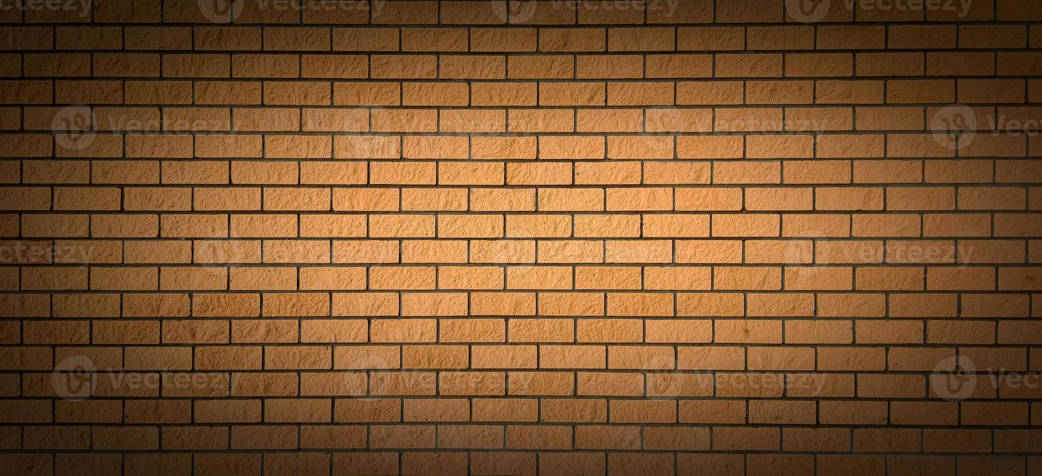 A brick wall with a light spot in the centre and a shadow at the edges. Perfect background for emphasizing important ideas. photo