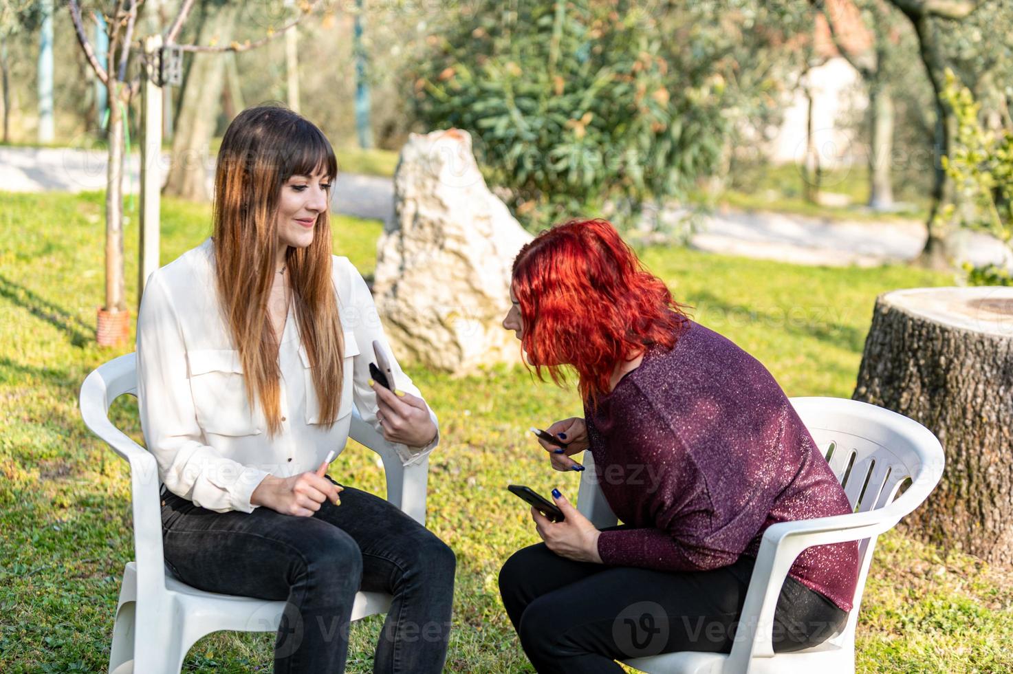 amigas usando teléfonos inteligentes y fumando cigarrillos foto