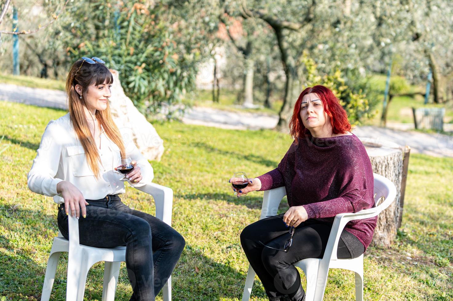 Las niñas beben vino en copa en el jardín. foto