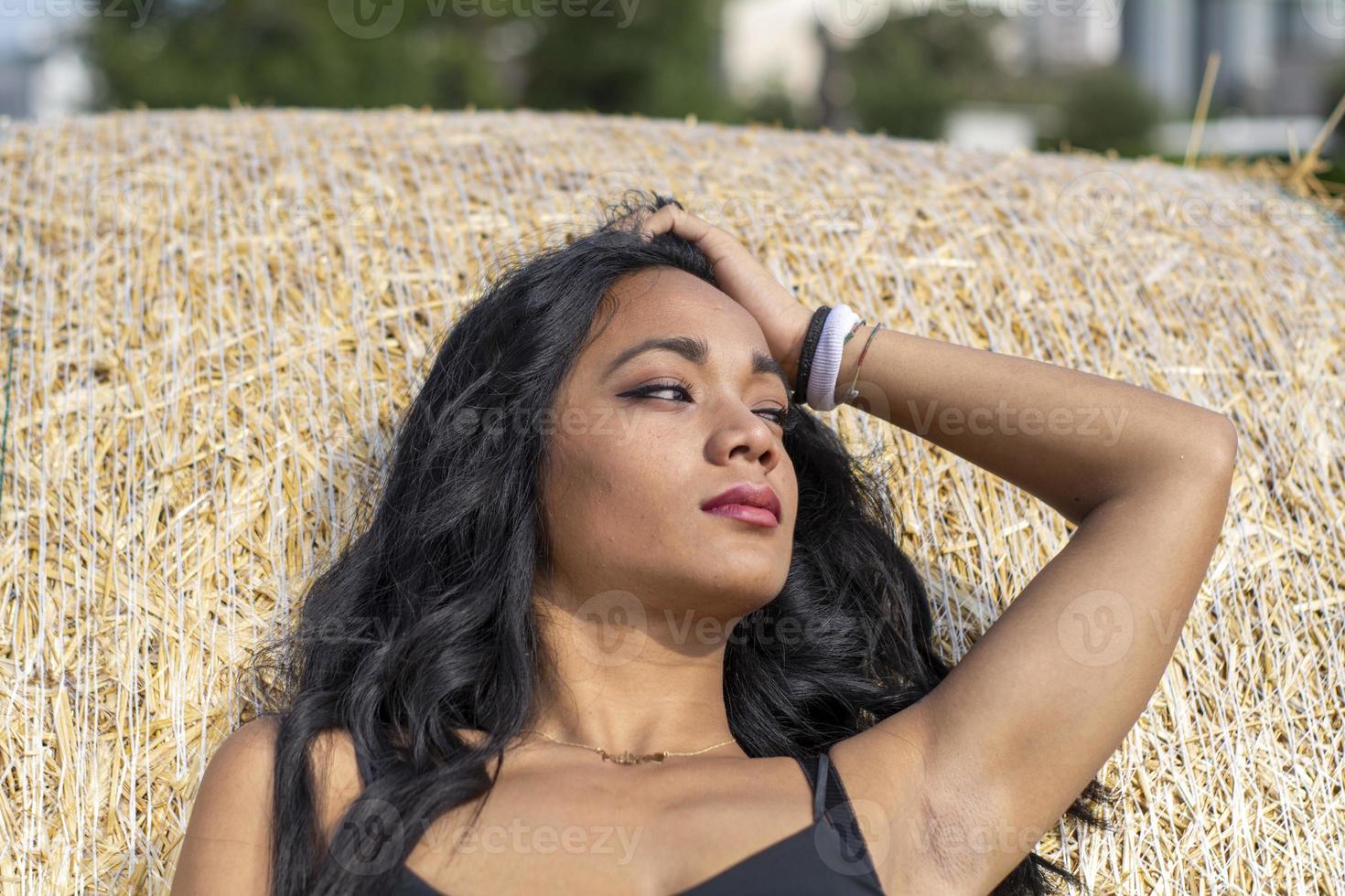 Indian girl leaning against a hay bale photo