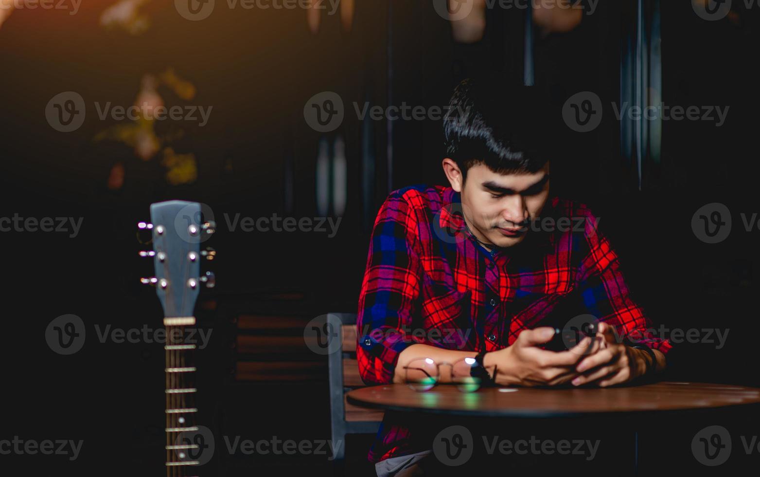 hombre enviando mensajes de texto con la guitarra junto a él foto