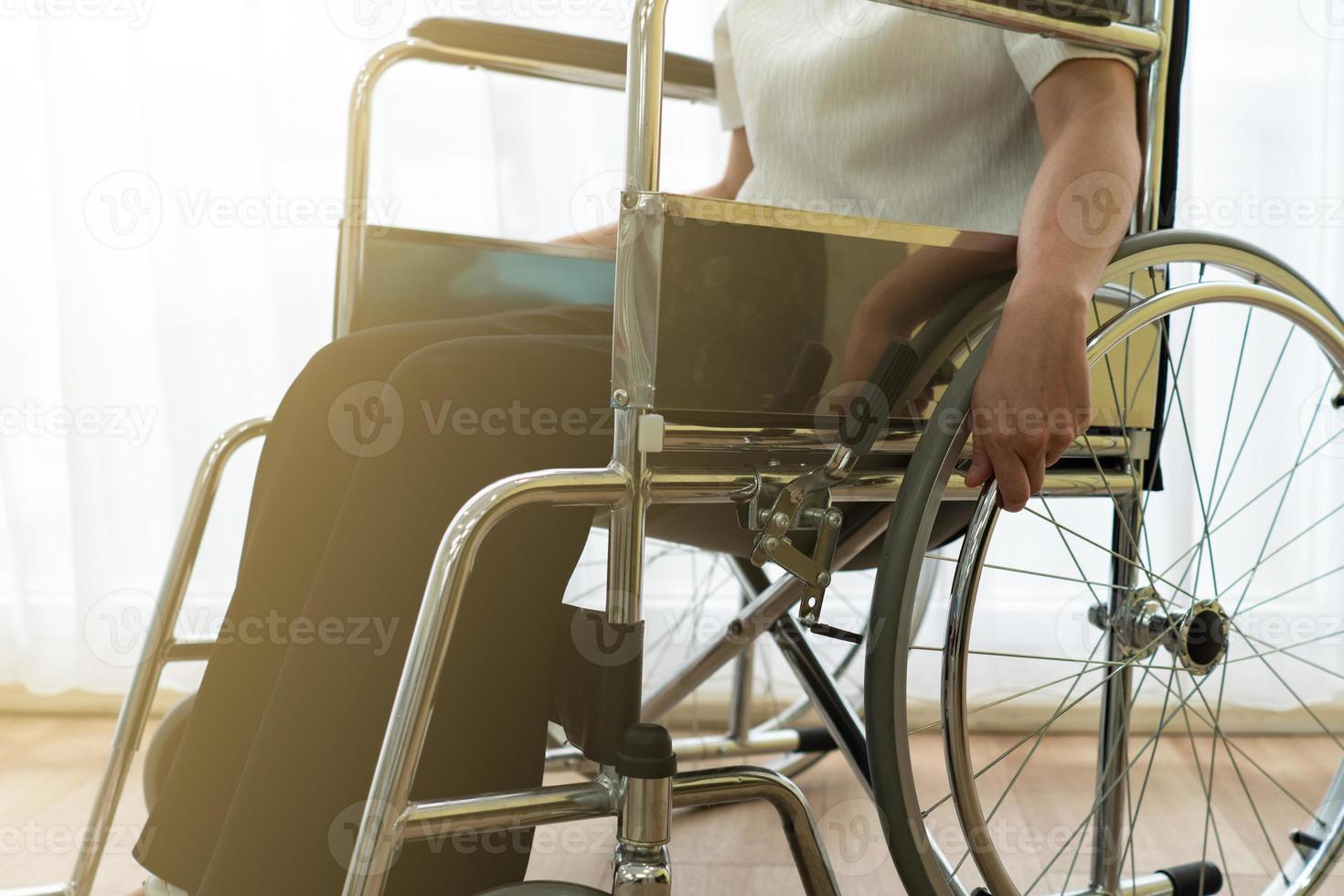 Mujer asiática joven discapacitada con sentimiento feliz y esperanzado sentado en la silla de ruedas sola en la casa. concepto de discapacidad y discapacidad foto