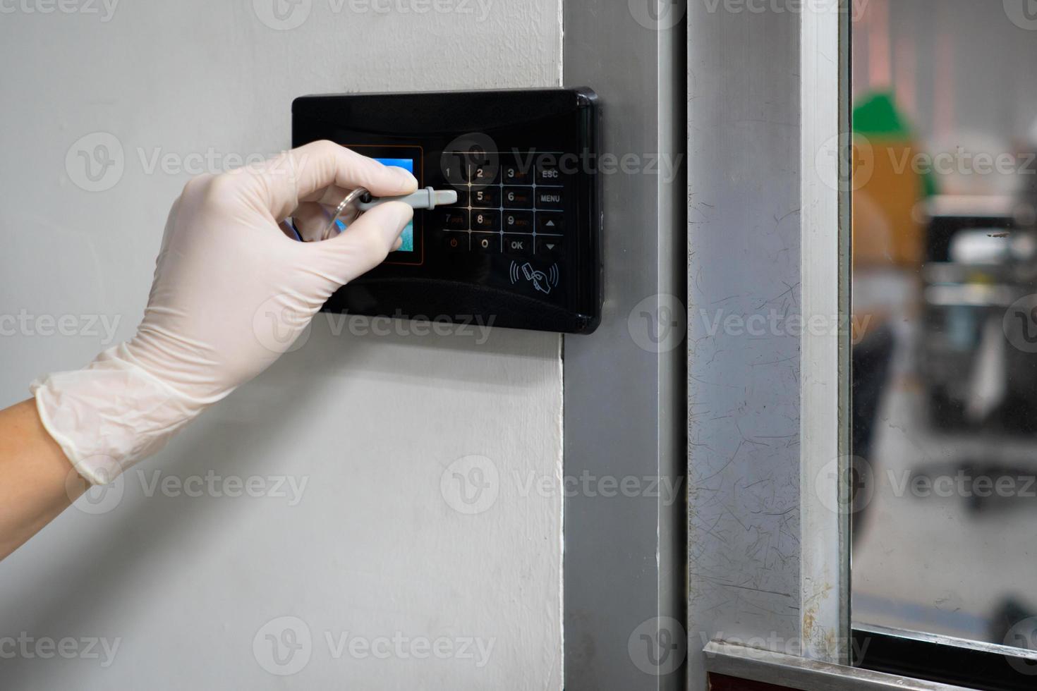 Hand wearing gloves to press password on digital door lock photo