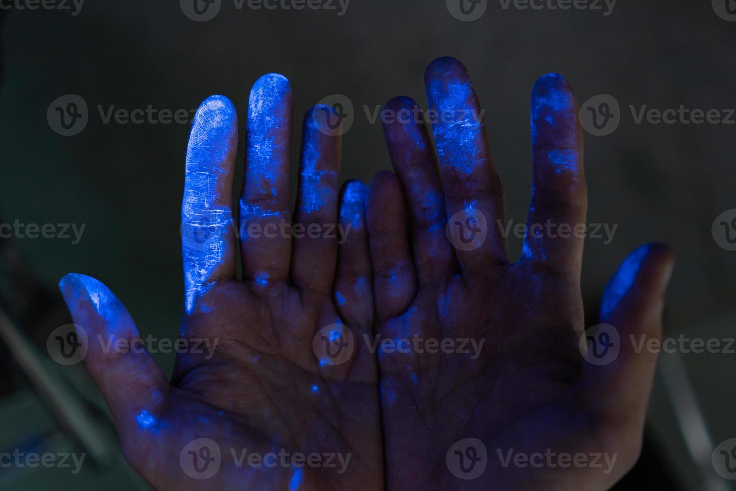 Hands covered in dust under a black light photo