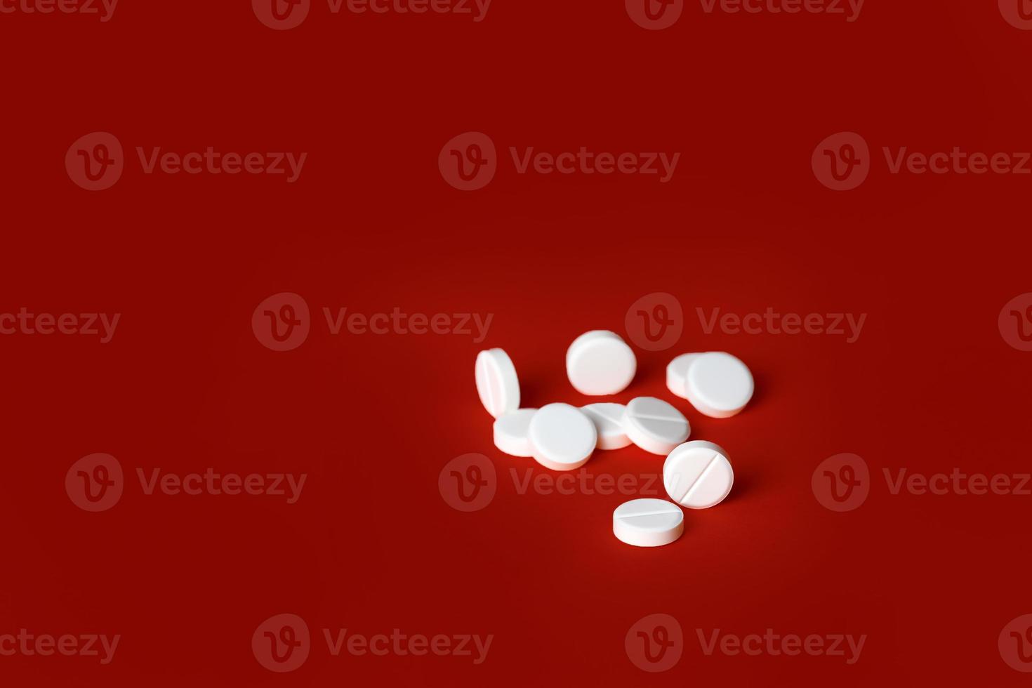 White medicine pills isolated on red background photo