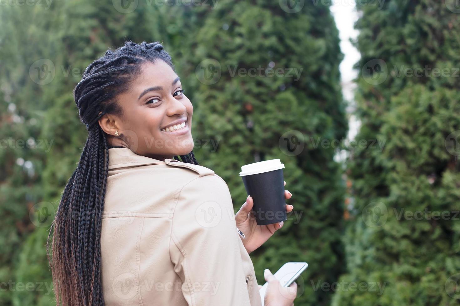 Feliz mujer afroamericana en la calle con café foto