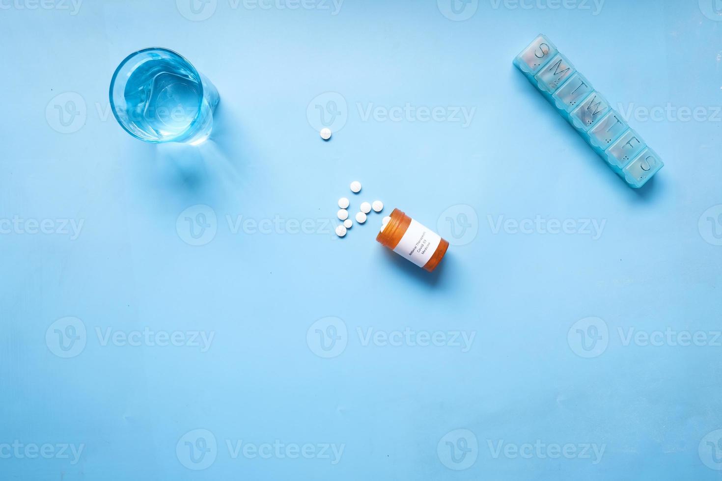 covid 19 medical pills and glass of water on blue background photo