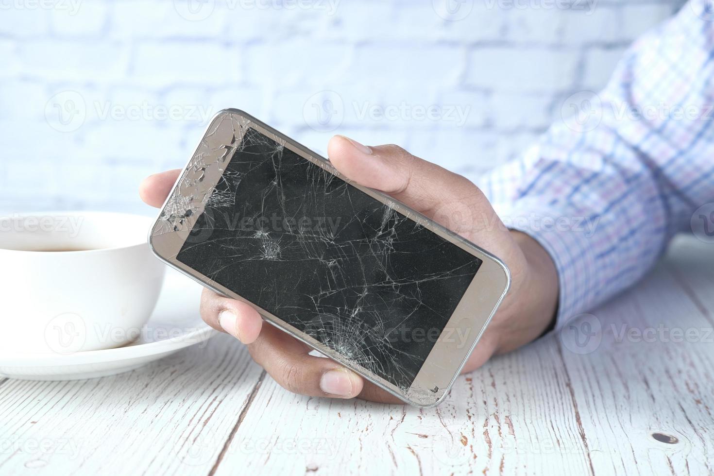 Close up of man hand holding broken smart phone. photo