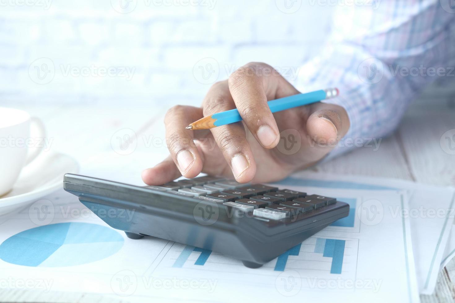 Close up of man hand using calculator with financial data on table photo