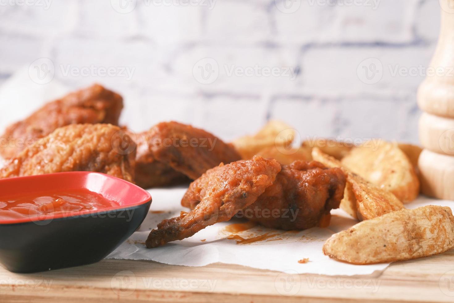 Pollo a la parrilla y gajos de camote en una tabla foto