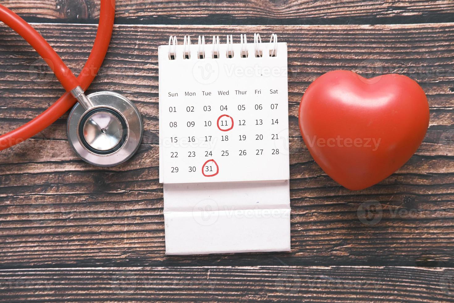 Estetoscopio, calendario y símbolo de forma de corazón en la mesa foto