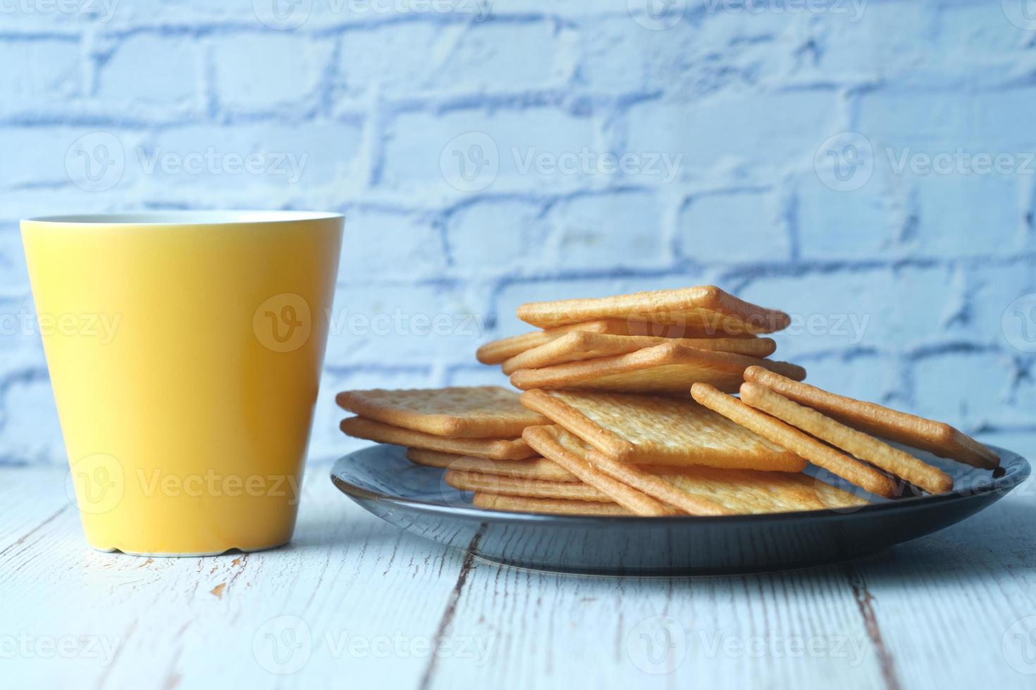 Cerca de galletas dulces y taza de café amarilla en la mesa foto