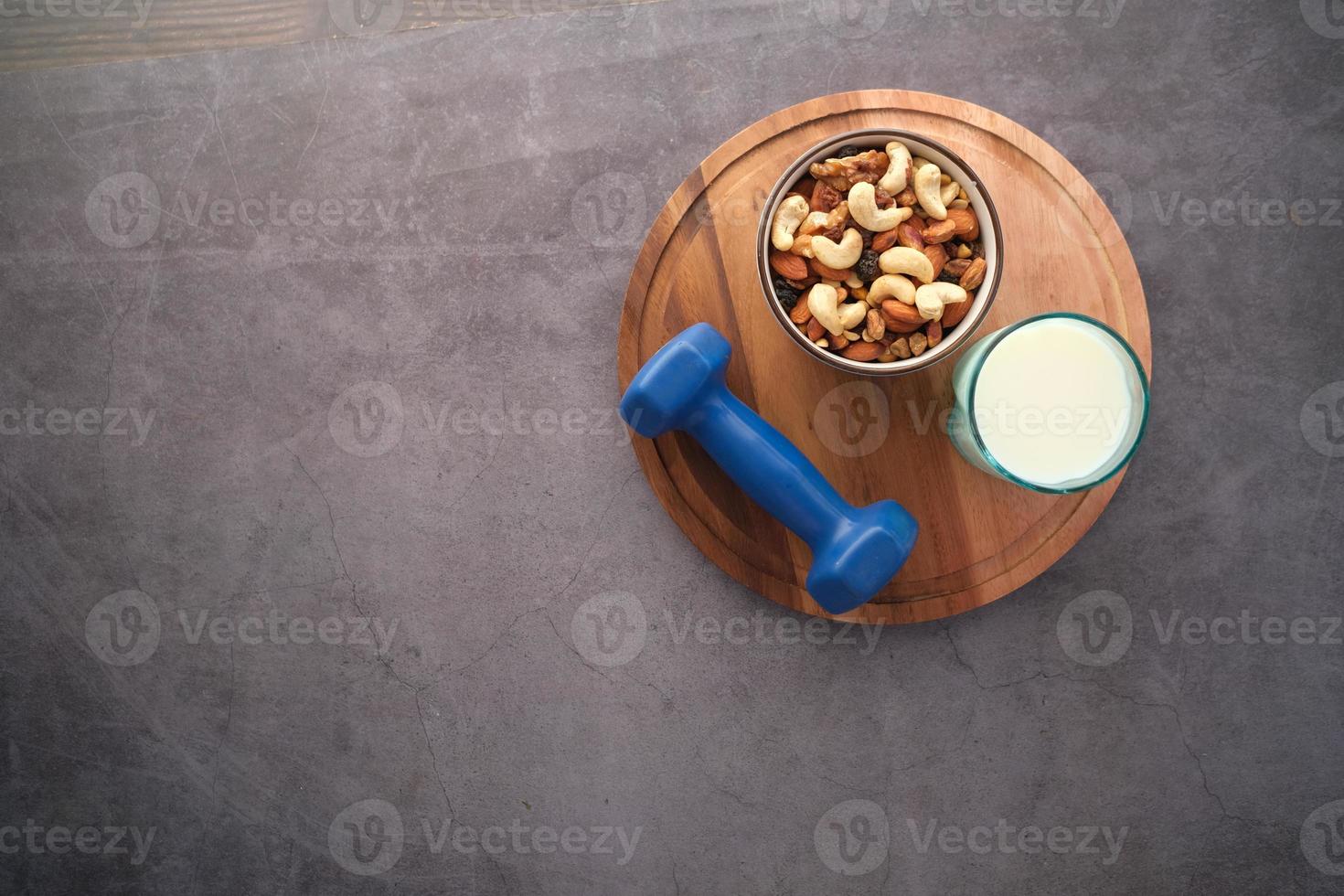 top view of glass of milk , dumbbell and mixed nuts in jar on black background photo