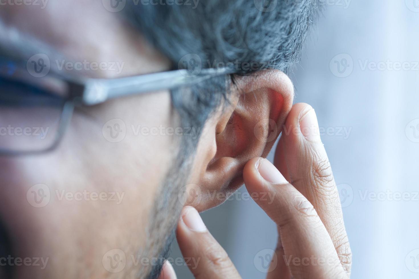 young man having ear pain touching his painful ear , photo