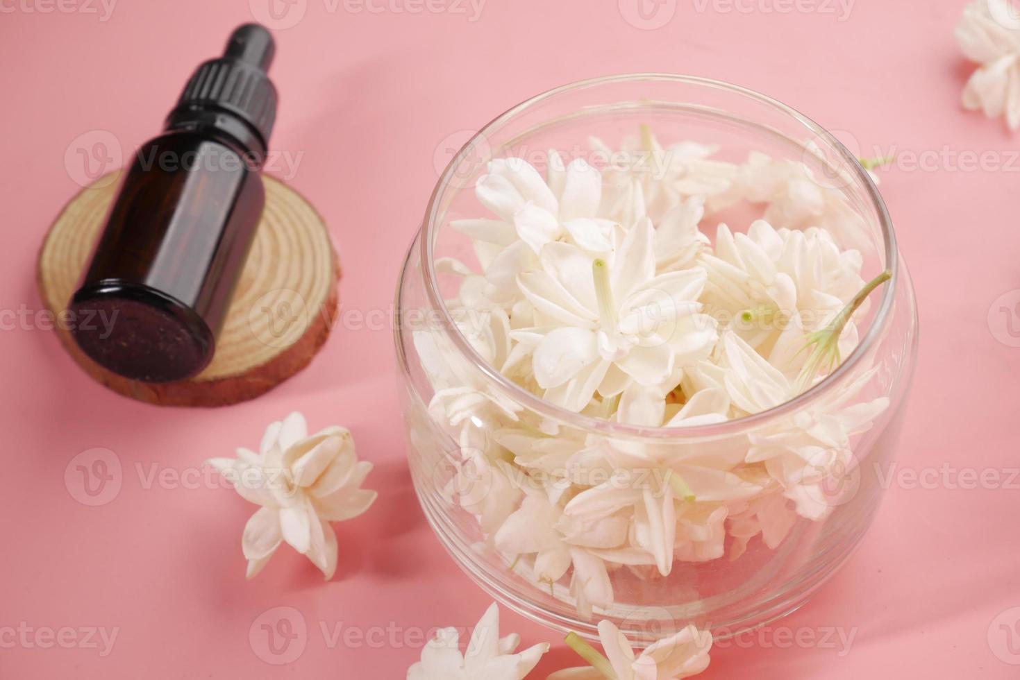 Aceites esenciales de eucalipto en una botella de vidrio y flor sobre fondo rosa foto