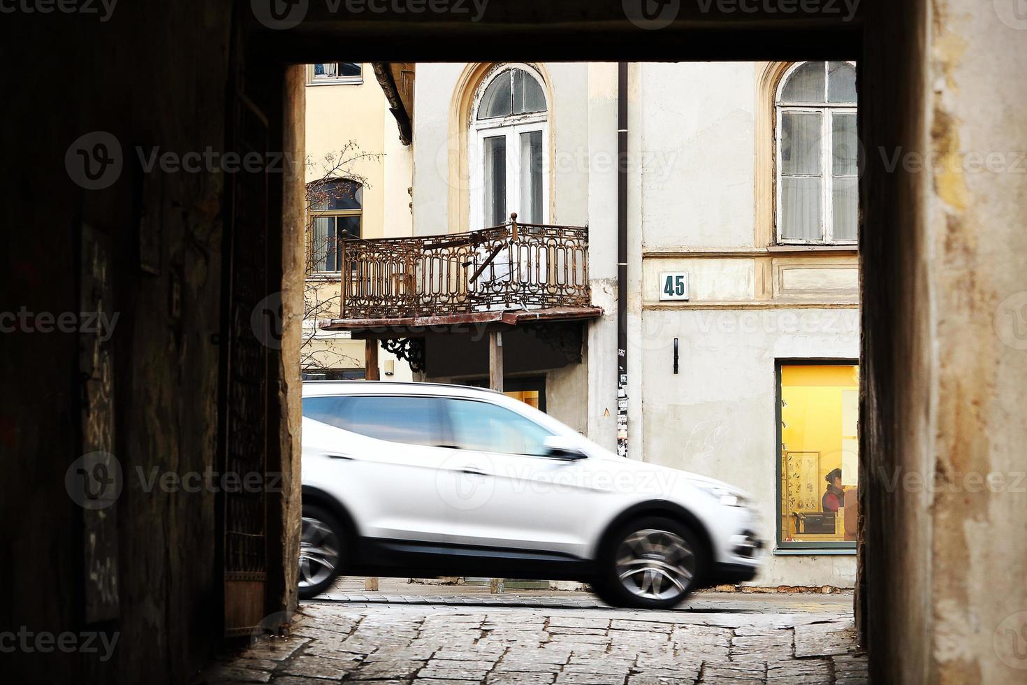 Puerta de la ciudad vieja con calle visible y coche gris foto